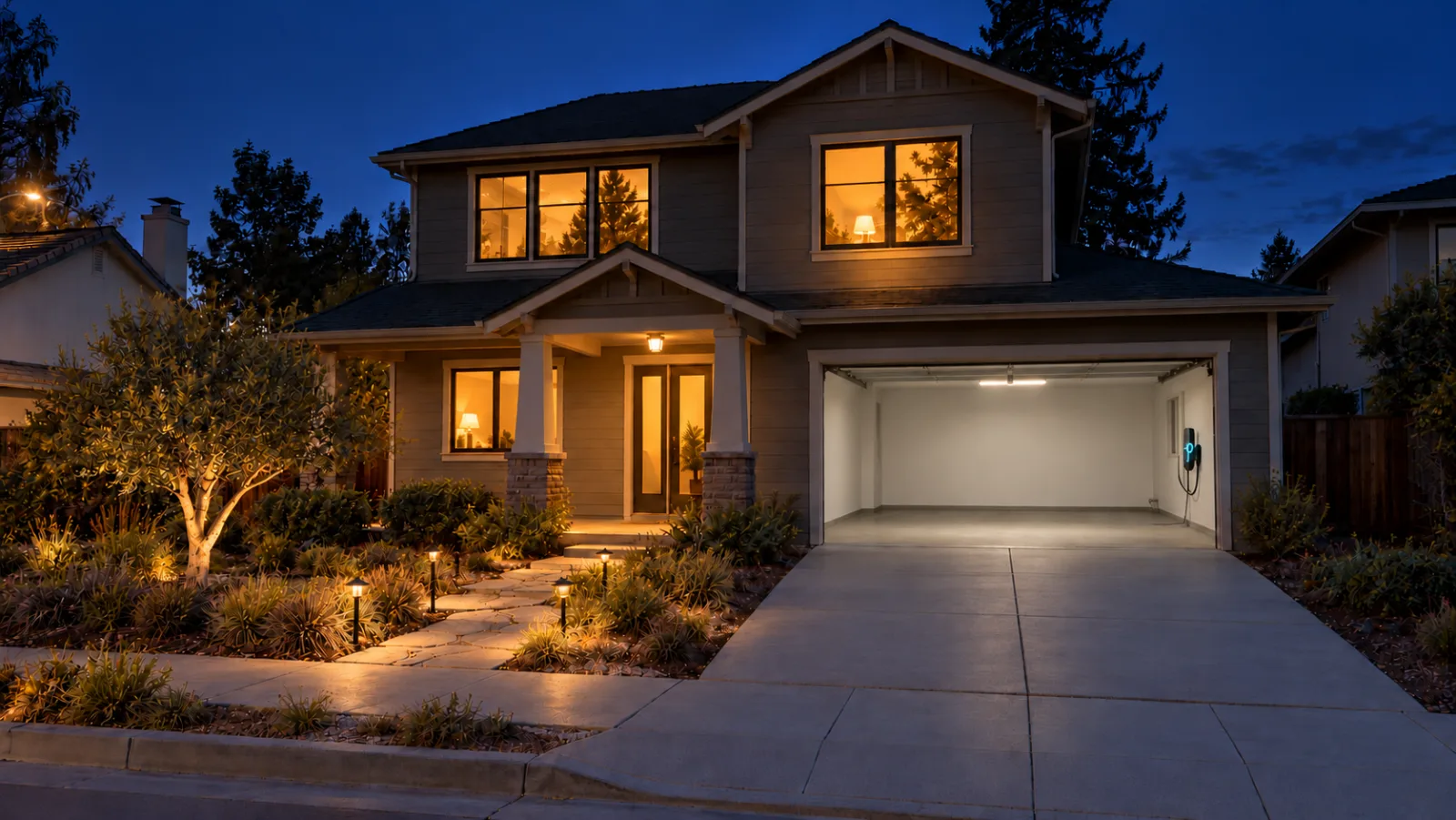 A two-storey Sunnyvale home at night with every window lit, the garage open with an EV charger glowing and path lights on.