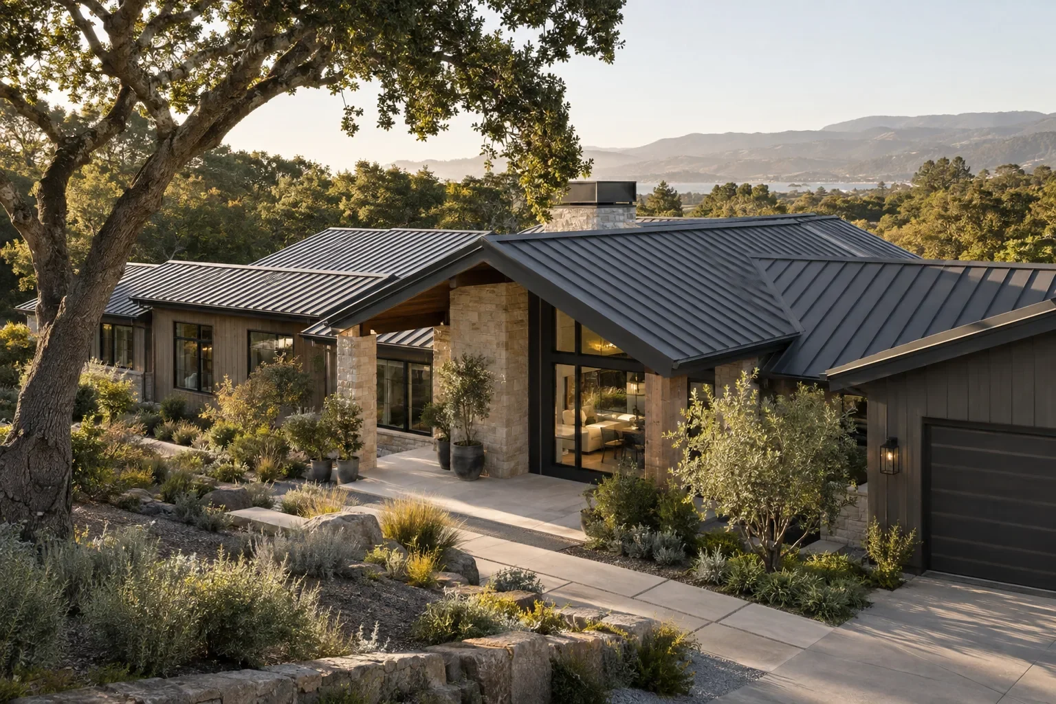 A gabled metal roof over a stone and timber home among oak trees