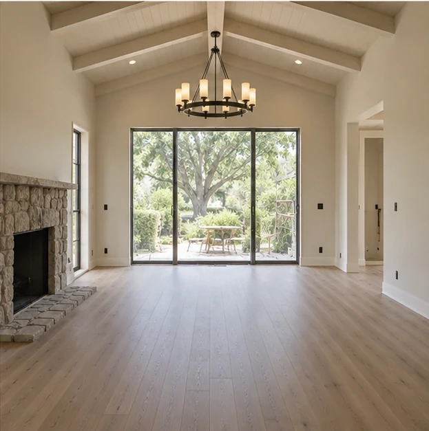 A finished living room with a vaulted ceiling, an iron chandelier, a stone fireplace and new wood flooring.
